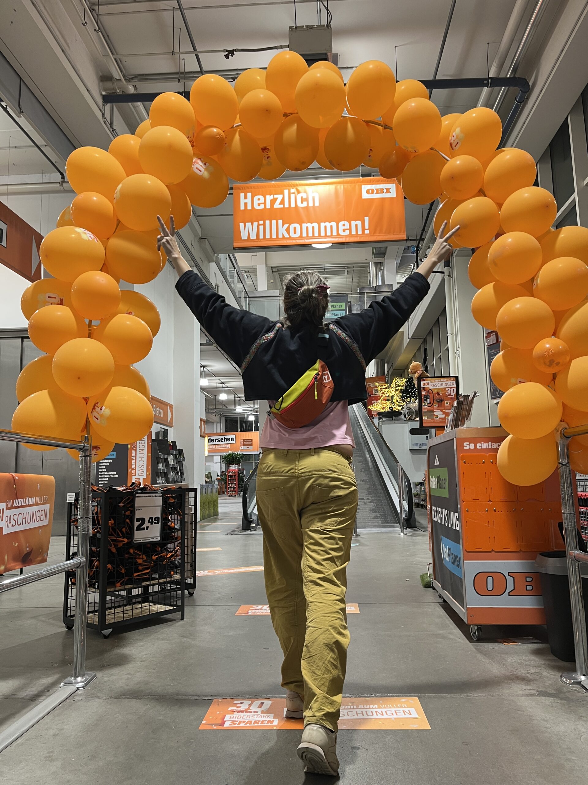 Kontakt Martina geht durch einen Bogen aus orangen Luftballons. 